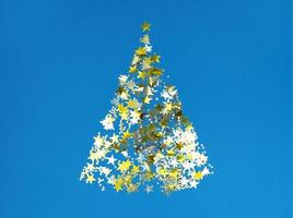 forma di albero di natale da stelle di coriandoli dorati su carta blu.
