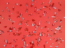 pezzi di lamina di coriandoli su sfondo rosso. sfondo festivo astratto. foto