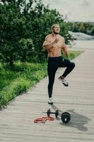 in forma barbuto uomo riscalda su all'aperto, fa alto ginocchio rubinetto esercizio, prepara per in esecuzione. cardio addestramento, forte corpo, determinato mentalita. foto