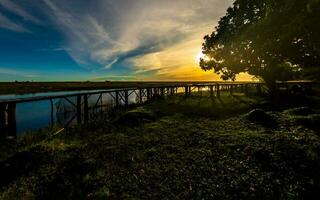 bellissimo tramonto paesaggio con di legno ponte foto