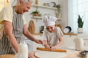 contento famiglia nel cucina. nonna e nipotina bambino cucinare nel cucina insieme. nonna insegnamento ragazzo ragazza rotolo su Impasto infornare biscotti. domestico lavoro di squadra porzione famiglia generazioni concetto. foto