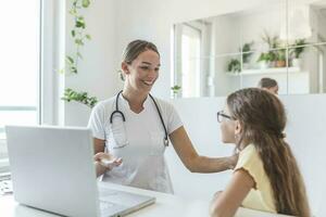 tiro di un' medico avendo un' consultazione con un' poco ragazza nel sua consulenza camera. 7 anno vecchio femmina paziente A proposito di con sua pediatra nel un' medici ufficio foto