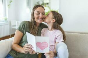 contento La madre di giorno. bambino figlia si congratula mamma e dà sua cartolina. mamma e ragazza sorridente e abbracciare. famiglia vacanza e solidarieta. foto