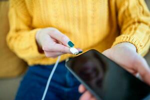 donna mani tamponamento un' caricabatterie nel un' inteligente Telefono. donna utilizzando smartphone con accumulatore di energia, ricarica energia per inteligente Telefono. donna ricarica batteria su mobile Telefono a casa foto