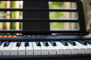 avvicinamento di pianoforte chiavi. pianoforte nero e bianca chiavi e pianoforte tastiera musicale strumento posto a il casa balcone durante soleggiato giorno. foto