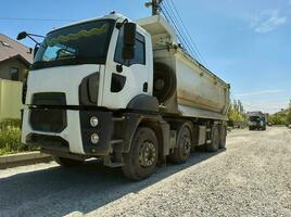 un' camion trasporto costruzione sabbia o calcestruzzo. il concetto di ricaricare su il strade e Noleggio un' cumulo di rifiuti camion per opera foto