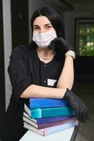 autentico bellissimo esperto femmina medico nel elegante nero uniforme, medico maschera e guanti, con medico letteratura foto