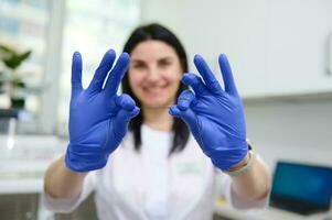 messa a fuoco su dentale filo per orale igiene e dentale cura nel il mani di un' sfocato sorridente femmina dentista medico igienista foto