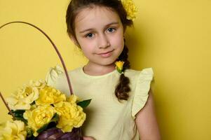 avvicinamento bellissimo blu con gli occhi poco ragazzo ragazza nel giallo vestito e fiori nel acconciatura, Tenere di vimini cestino con fiore foto