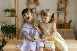 poco contento ragazze scemo in giro nel il cucina e mangiare mele foto