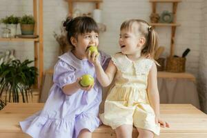 poco contento ragazze scemo in giro nel il cucina e mangiare mele foto