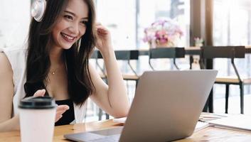 donna asiatica che indossa le cuffie che studia online guardando un podcast webinar sul laptop, ascoltando e imparando le chiamate in conferenza del corso di formazione, concetto di e-learning foto