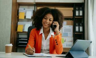 africano donna d'affari Lavorando nel il ufficio con Lavorando bloc notes, tavoletta e il computer portatile documenti foto