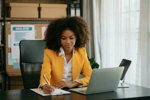 fiducioso attività commerciale esperto attraente sorridente giovane donna digitando il computer portatile ang Tenere digitale tavoletta su scrivania nel creativo ufficio. foto