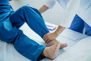 fisioterapista porzione paziente mentre allungamento il suo gamba nel letto nel clinica foto
