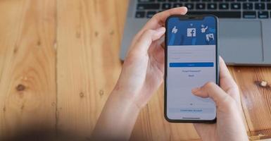 chiang mai, thailandia 18 agosto 2020 - donna in possesso di un iphone x con servizio social internet facebook sullo schermo. foto
