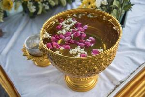 acqua nel mestolo d'acqua con piedistallo di fiori colorati per il festival di songkran, tailandia foto