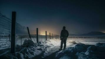 un' solitario soldato in piedi guardia a un' confine inviare durante un' gelido inverno notte foto