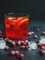 aperol spritz con ghiaccio e mirtilli rossi su sfondo nero.
