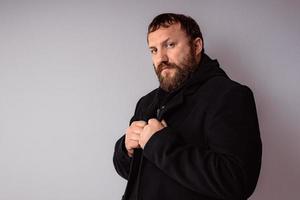 bell'uomo elegante con la barba che indossa un cappotto nero foto