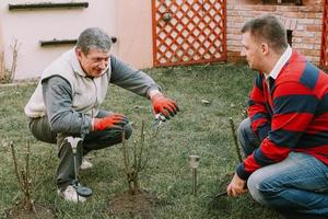 giovane adulto maturo che aiuta il maschio anziano con il lavoro di giardinaggio foto