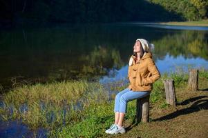 donna rilassante viso occhi chiusi seduto in riva al fiume. foto