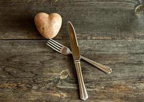patate rosse a forma di cuore su uno sfondo di legno con forchetta e coltello. il concetto di agricoltura, raccolta, vegetarianismo. San Valentino. quadrato, cibo brutto. foto