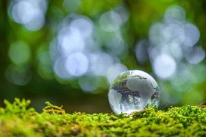 concetto salva il mondo salva ambiente il mondo è nell'erba dello sfondo verde bokeh foto