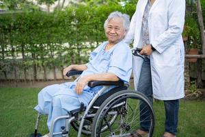 medico aiuto e cura asiatico anziano o anziana signora anziana paziente seduta su sedia a rotelle al parco nel reparto ospedaliero di cura, concetto medico sano e forte. foto
