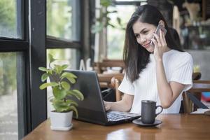 bella ragazza d'affari che lavora con tablet, smartphone e beve caffè nella caffetteria foto