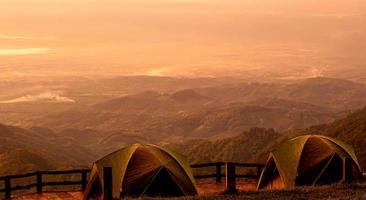 due tende si erge sullo sfondo di un bellissimo paesaggio di montagna con la calda luce del tramonto.
