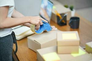 attività commerciale a partire dal casa asiatico donna preparazione pacchetto consegna scatola spedizione per shopping in linea. giovane inizio su piccolo attività commerciale proprietario a casa in linea ordine foto