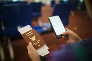 donna in attesa per partenza a il aeroporto su il tuo vacanza hold passaporto e smartphone mentre in attesa imbarco su partenza la zona internazionale aeroporto foto