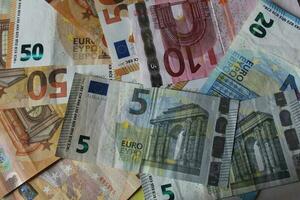 mucchio di banconote su il tavolo nel denominazioni di venti euro, cinquanta euro, dieci euro, cinque euro. sfondo di misto Euro banconote foto