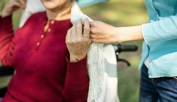 famiglia relazione asiatico anziano donna nel sedia a rotelle con contento figlia Tenere badante per un' mano mentre la spesa tempo insieme foto