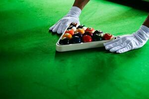 dell'uomo mano e spunto braccio giocando snooker gioco o preparazione mirando per sparare piscina palle su un' verde biliardo tavolo. colorato snooker palle su verde fregio. foto