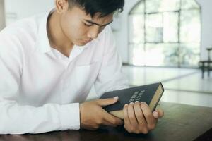 uomo pregando, mani stretto insieme su sua Bibbia. foto