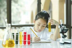 prescolastico ragazza è interessato nel laboratorio lezione, assunzione Appunti su libro per sua studia. foto