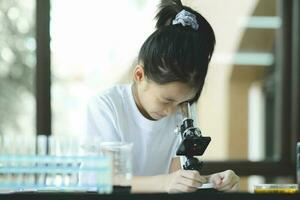 poco bambino con apprendimento classe nel scuola laboratorio utilizzando microscopio foto