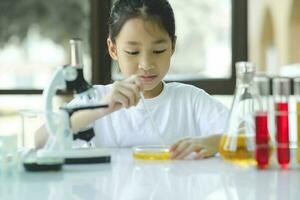 poco bambino con apprendimento scienza classe nel scuola laboratorio foto