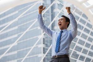 l'uomo d'affari tiene la mano dopo un business di successo e sta in piedi all'aperto con un edificio per uffici sullo sfondo foto