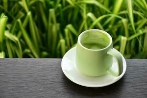 un' tazza di verde tè su di legno tavolo accanto fiore letto. foto