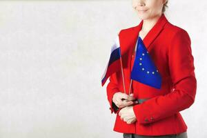 un' giovane donna fra 30 e 40 anni vecchio hold Due bandiere di Unione Europea e Russia. foto