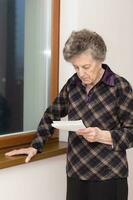 anziano donna è lettura qualcosa foto