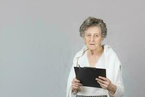 anziano vecchio donna a il grigio sfondo foto