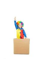 ragazzo di cinque anni vestito nel il costume di un' clown cerca per saltare a partire dal scatola di cartone carta scatola. foto
