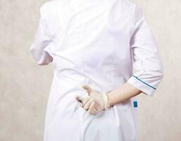 un' medico vestito nel un' professionale uniforme nasconde siringa con medicazione foto