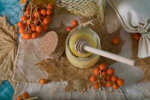 Rowan frutti di bosco, bicchiere con miele e Favo su un' tela di sacco. . foto