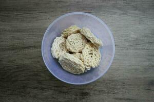 kerupuk o kerupuk warung è indonesiano tradizionale in profondità fritte cracker fatto a partire dal amido misto con sapori come come pesce, servito nel un' plastica contenitore su un' di legno tavolo. selettivo messa a fuoco. foto