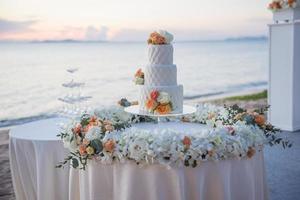torta nuziale al matrimonio sulla spiaggia al tramonto foto